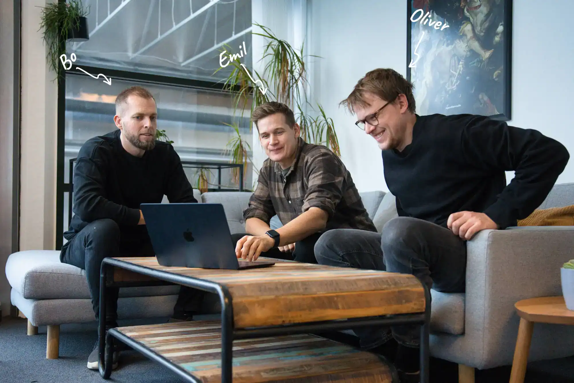 Bo, Emil og Oliver, der står bag Alunta, sidder på sofaen og hygger sig. Med kursiv hvid skrift er deres navne angivet.